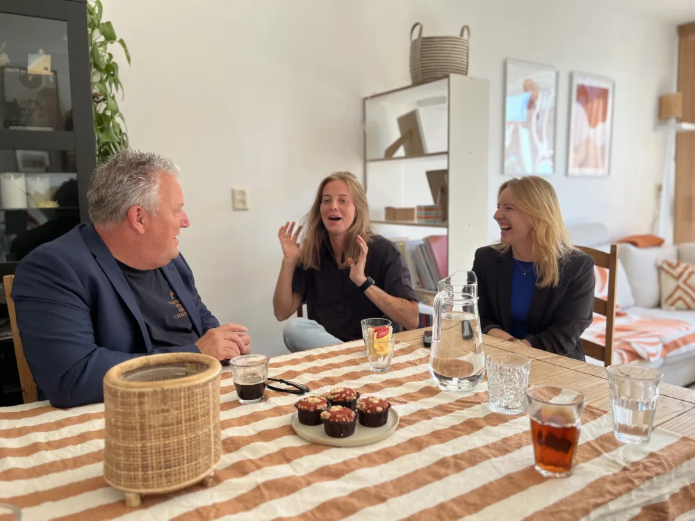 Drie mensen lachen samen aan de eettafel