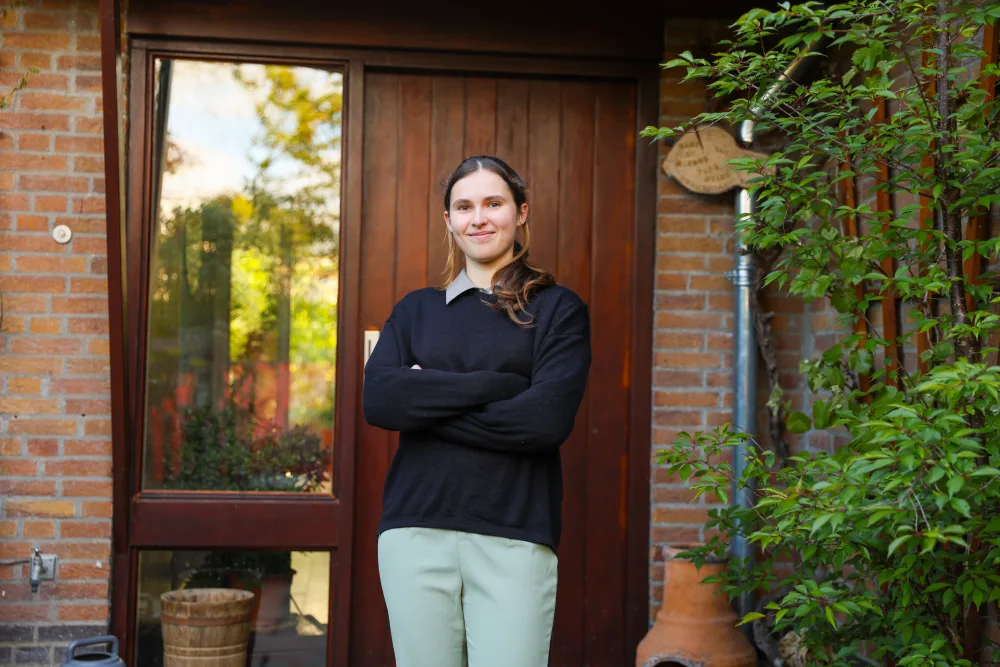 Een huurder staat voor de voordeur van haar woning